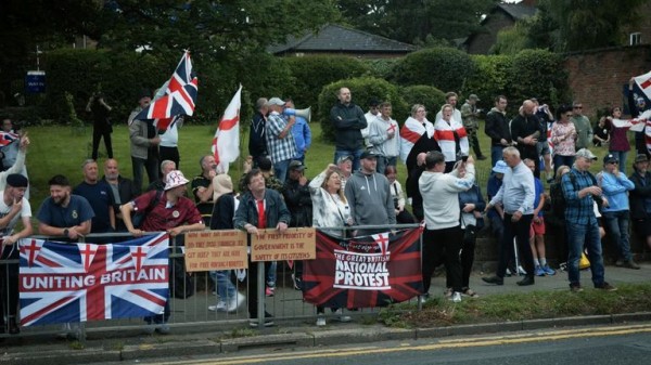 Rival groups face off outside migrant hotel - as asylum seekers 'blow kisses' at protesters Rival groups face off outside migrant hotel - as asylum seekers 'blow kisses' at protesters